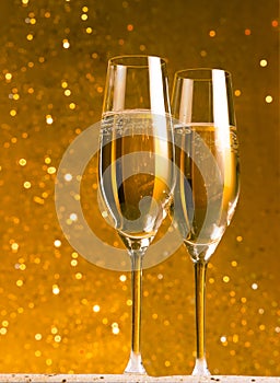 A pair of flutes of champagne on golden abstract background