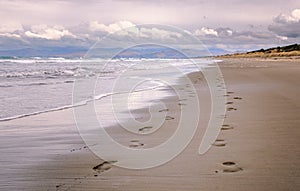 Pair of foot prints on a deserted beach on cloudy evening