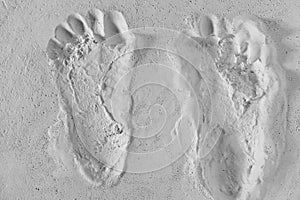 Pair of footprints cast in white textured sand