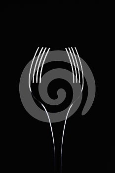 Pair of forks on black background look like a wine glass