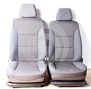 A pair of front row car seats made of gray fabric isolated on a white background in a photo studio shot from the interior of a