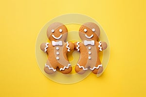 Pair of gingerbread men with bow ties on yellow background