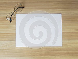 A pair of glasse on a sheet of paper and wooden background