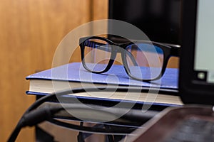 Pair of glasses on a book against a computer on the table