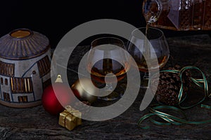 pair of glasses and bottle of liquor on decorated Christmas table with black background