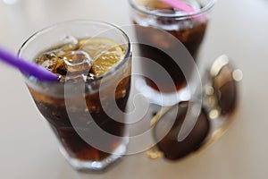 Pair of glasses filled with coca cola with lemon and ice cubes, cooling summertime drinks