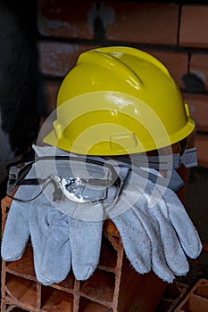 Gloves, helmet and mason`s goggles on pile of bricks photo