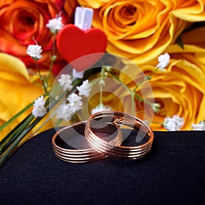 Pair of gold wedding rings and a bouquet of roses