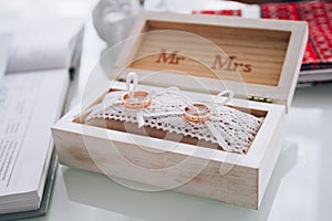 A pair of golden wedding rings lying in a white wooden box. Wedding decoration. Symbol of family, unity and love