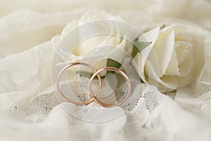 Pair of golden wedding rings over invitation card decorated with lace