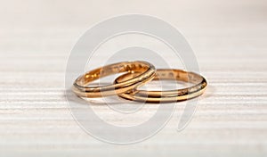 Two golden wedding rings on white wooden background