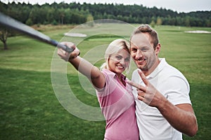 A pair of golfers make a photo on the golf course using a stick like a sephi pole