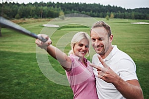 A pair of golfers make a photo on the golf course using a stick like a sephi pole