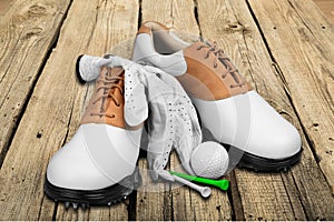 Pair of golfing shoes, ball and tees on wooden
