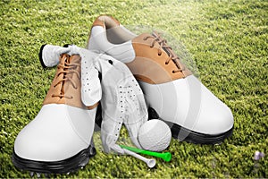 Pair of golfing shoes on green grass background