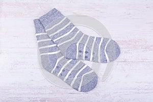 Pair of gray woolen socks on white wooden background