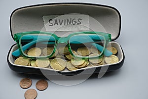 A pair green glasses in a black case,with some coins, with written savings