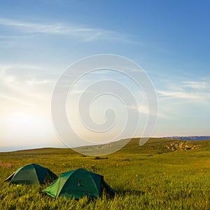 pair of green touristic tent at the sunset