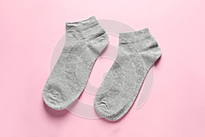 Pair of grey socks on pink background, flat lay
