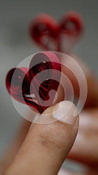 A pair of hands gently hold a quilled paper heart