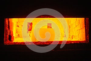 A pair of heavy hot yellow glowing cylindrical workpieces heating up inside gas furnace