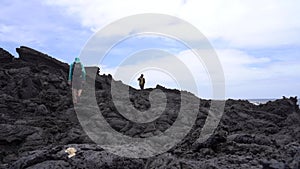 Pair of hikers walking through lava fields in Timanfaya national park, Lanzarote, Canary Islands
