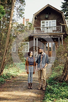 A pair of hipsters in a forest near an old house