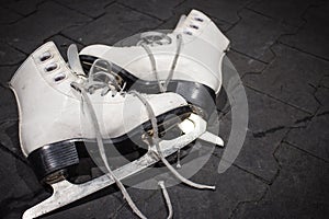 Pair of ice figure skates on black background. Winter sport activity. White ice skates with blade, isolated. Fun and hobby concept