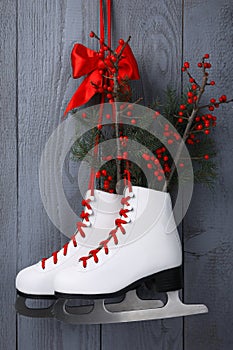 Pair of ice skates with Christmas decor hanging on grey wooden wall