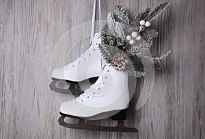 Pair of ice skates with Christmas decor hanging on wooden wall