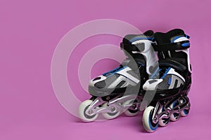 Pair of inline roller skates on color background