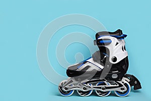 Pair of inline roller skates on color background