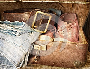 Pair of jeans, shoes, belt in a vintage suitcase