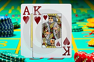 A pair of king and ace of hearts of playing cards on green background of a gaming table in a casino. Close up of