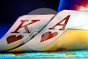 A pair of king and ace of hearts suit playing cards on a blue background of a gaming table in a casino. Close up of