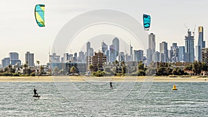 Pair of kitesurfers trains in Port Phillip Bay, with the skyline of Melbourne, Australia in the background photo