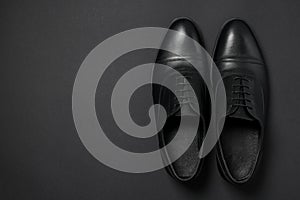 Pair of leather men shoes on black background, top view. Space for text