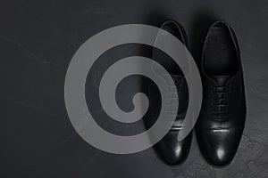 Pair of leather men shoes on black surface, top view. Space for text