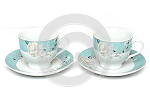 A pair of light colored teacups with saucers