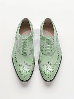 Pair of light green leather brogue shoes on white background.