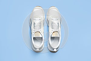 Pair of light men`s sneakers on blue background. Sports shoes, footwear for fitness, running, training. Minimalistic background