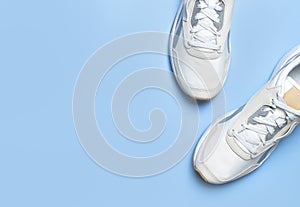 Pair of light men`s sneakers on blue background. Sports shoes, footwear for fitness, running, training. Minimalistic background