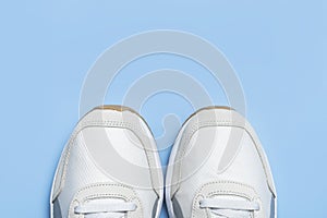 Pair of light men`s sneakers on blue background. Sports shoes, footwear for fitness, running, training. Minimalistic background