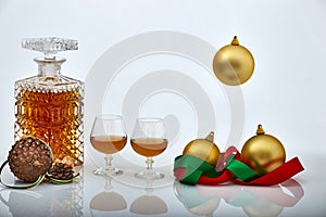 Pair of liquor glasses and bottle with Christmas ornaments, white backgrounds and reflections