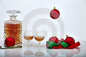 Pair of liquor glasses and bottle with Christmas ornaments, white backgrounds and reflections