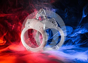 Pair of locked handcuffs with red and blue smoke