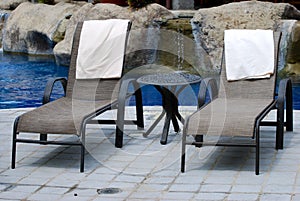 A pair of lounge chairs by a pool