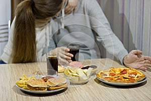 A pair of lovers sit at the table and eat fast food.