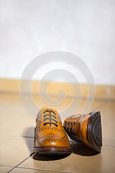 Pair of Luxury Male Full Brogued Tan Oxford Shoes. Placed Together on Tiles Floor