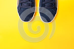 Pair of man's new sneakers made of blue leather on a yellow background. Copy space. Close up of shoes toes